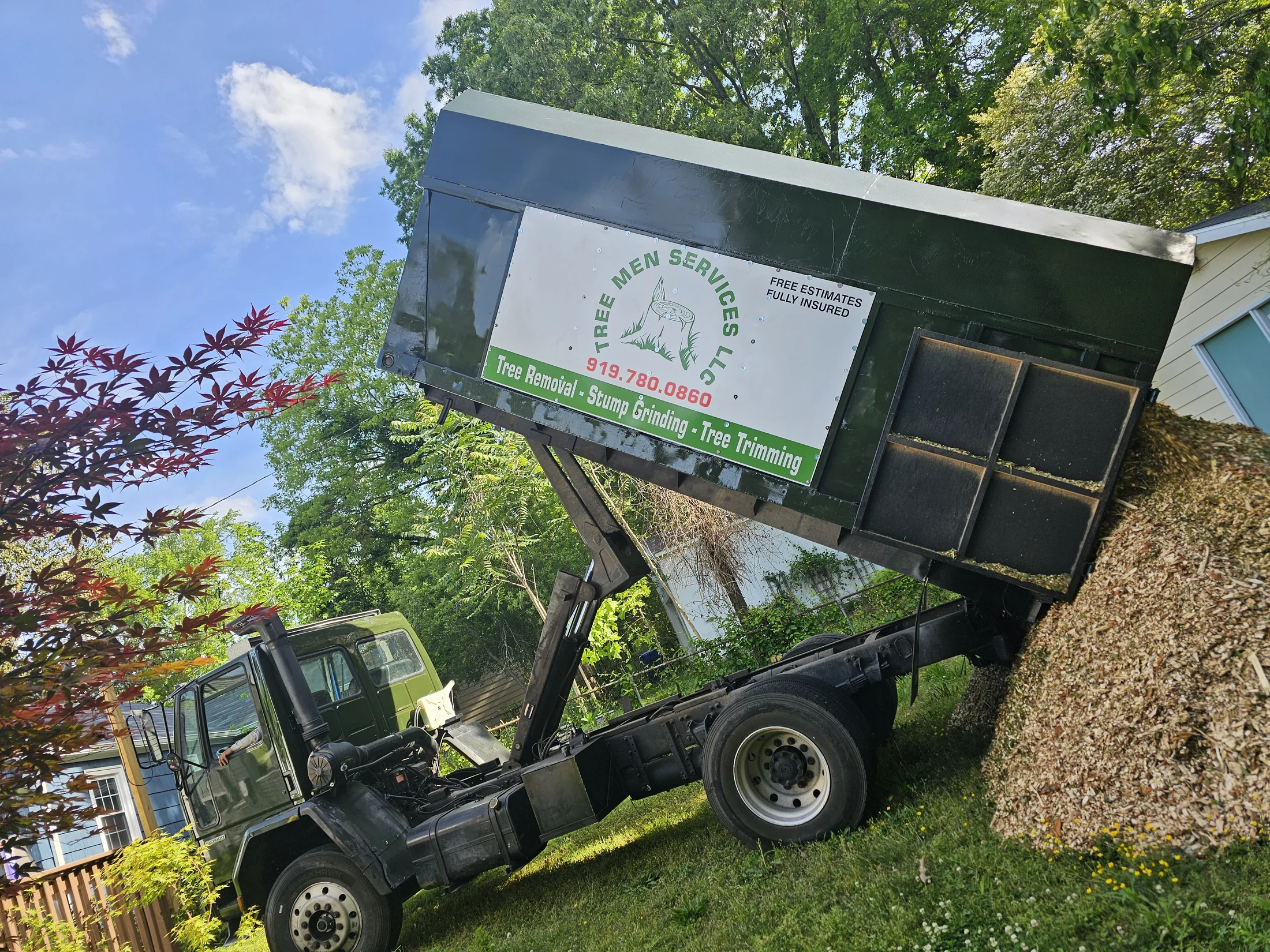 Tree Men Services branded hauling truck removing wood chips and debris from a property